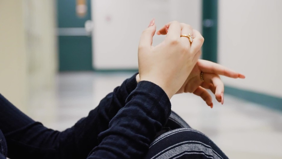 Hands of teenage girl sitting in hallway cracking fingers ClipStock