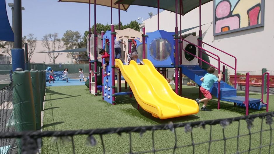 Static shot of kids going down slide on playground Slow Motion