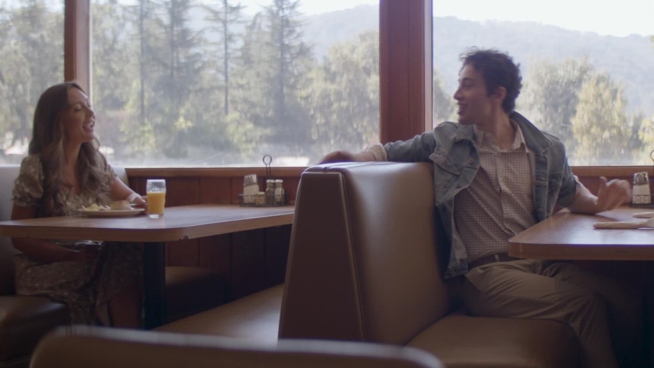 Happy young couple sitting in a booth in a diner while talking with a