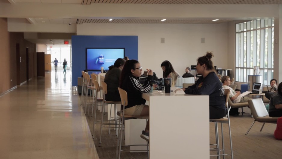 Rack focus of students eating and relaxing in campus lounge area