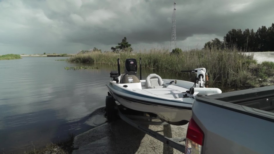 guy backing boat down ramp into river ClipStock
