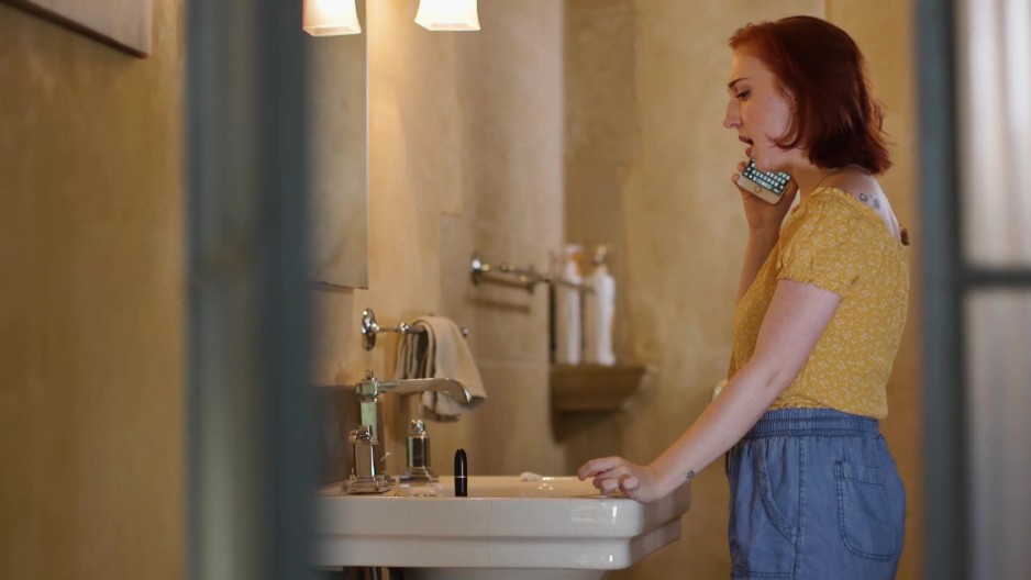 mid 20s girl standing in her bathroom talking on the phone while