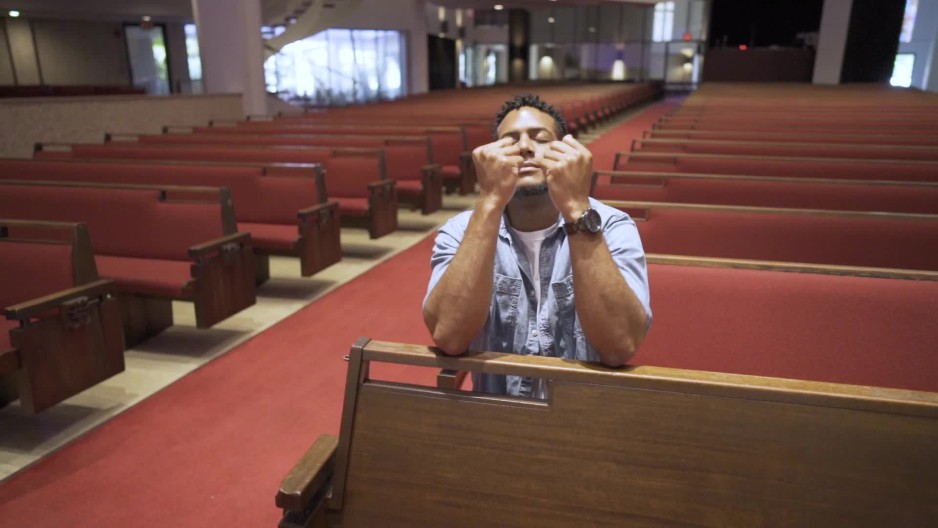 black man on his knees in the pews in a church praying to God - slow