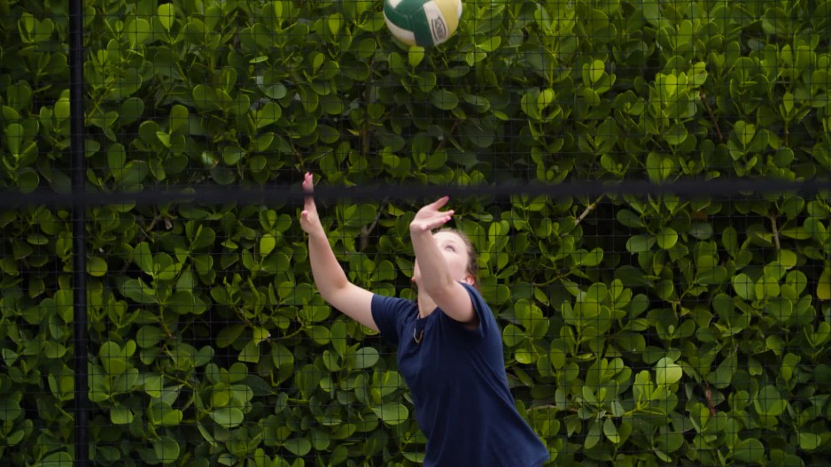 Athletic volleyball player serves ball over net ClipStock