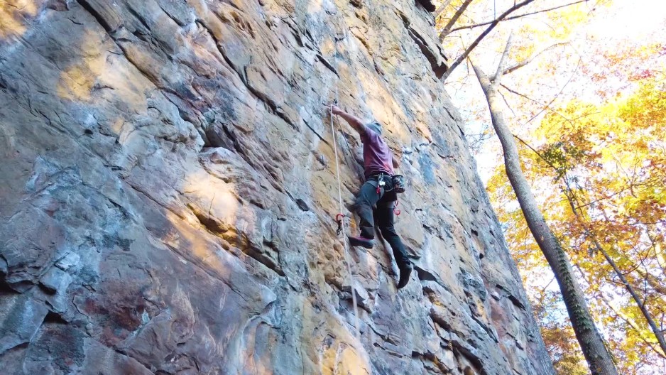 Adult male athlete lead climbing route on mountain wall placing