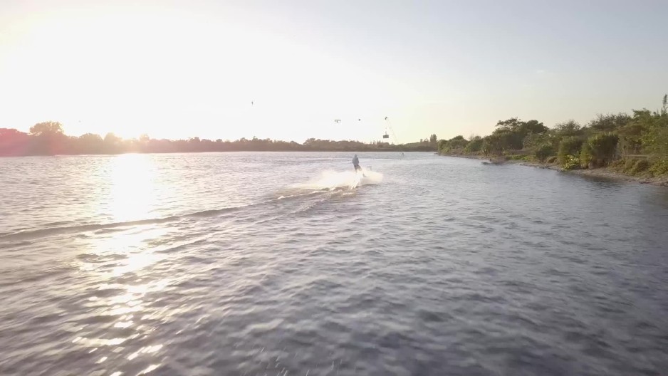 Aerial long shot of person wakeboarding at cable park during sunset