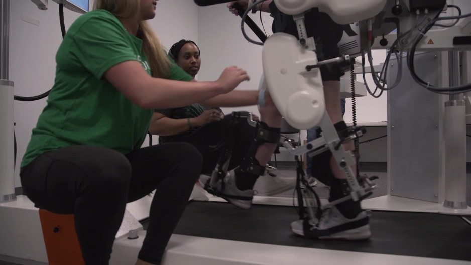 Legs of paraplegic patient walking on machine assisted unweighting