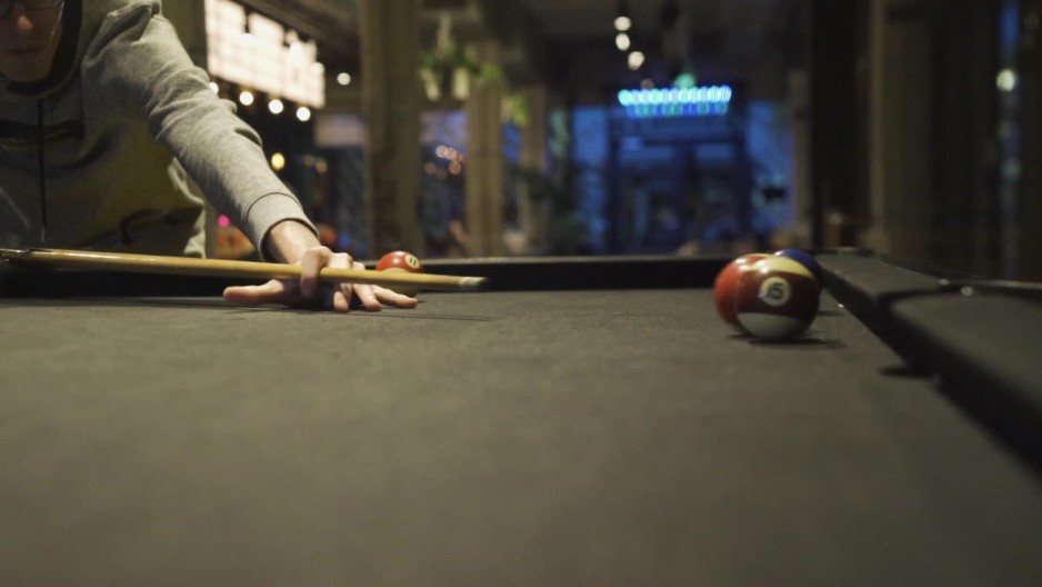 Man hitting and scattering multiple billiard balls with cue ball