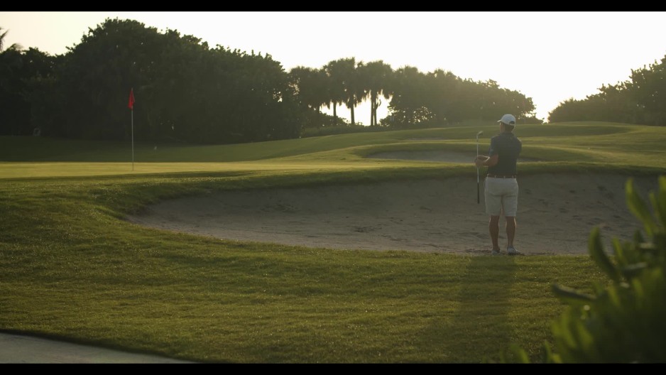Male golfer chipping golf ball out of sand trap slow motion ClipStock