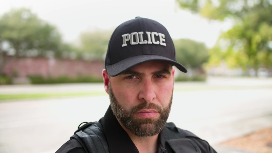Stern policeman standing outside staring following camera | ClipStock