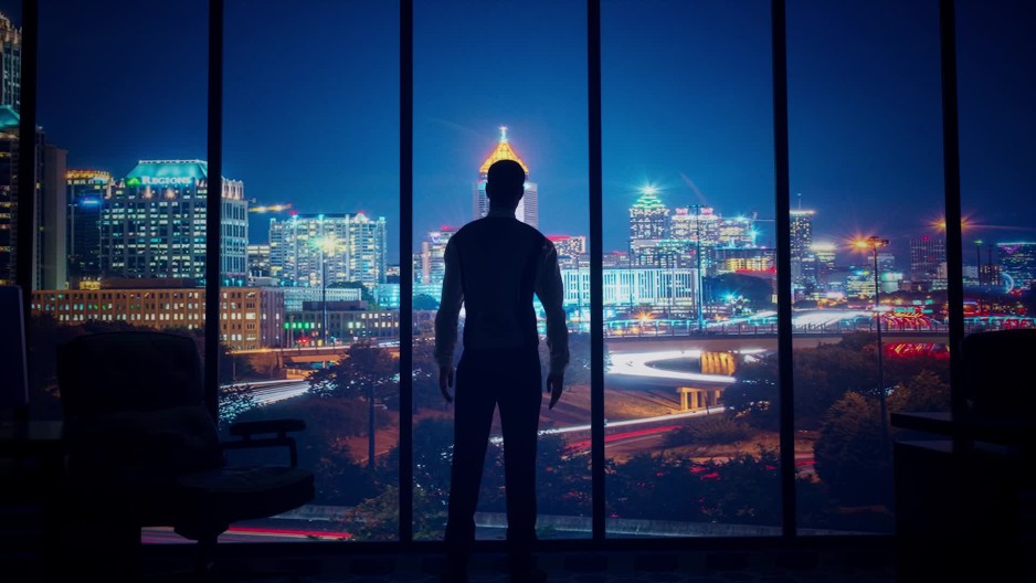 Silhouette man looking out office window at atlanta georgia skyline
