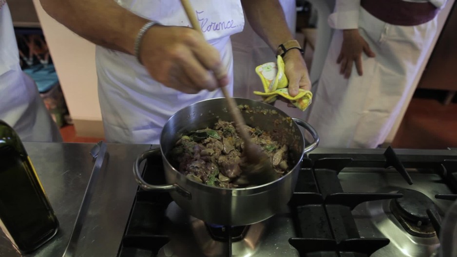 Tight of man stirring pot of meat and veggies in cooking class | ClipStock