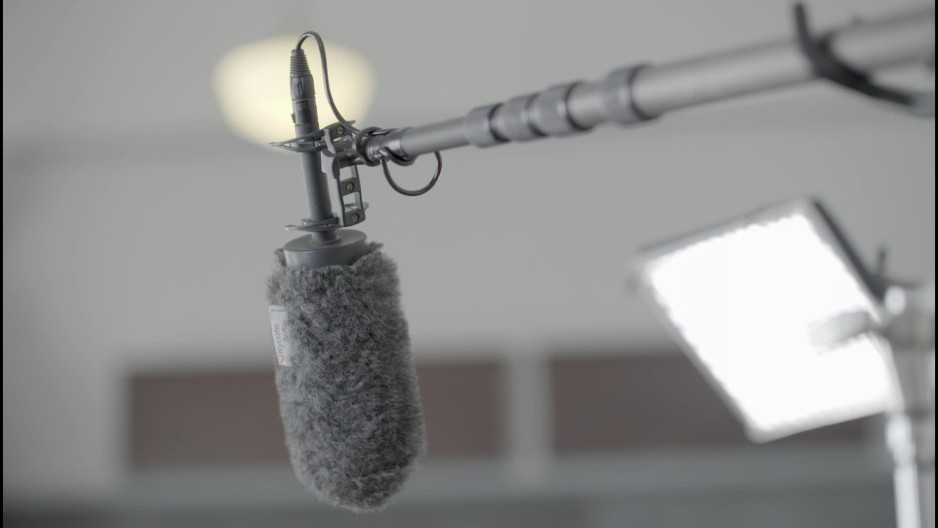 Close up of a boom microphone mounted over a film set ClipStock