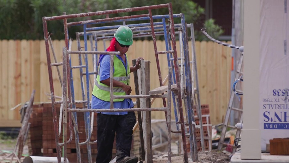 Construction worker setting up wood board beneath scaffolding on