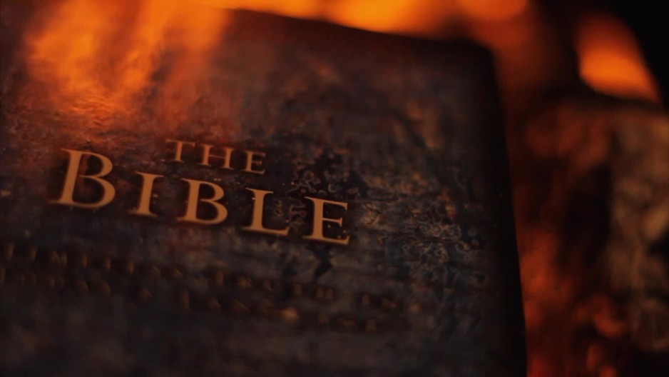 Extreme close up of the Bible with flames in the background | ClipStock