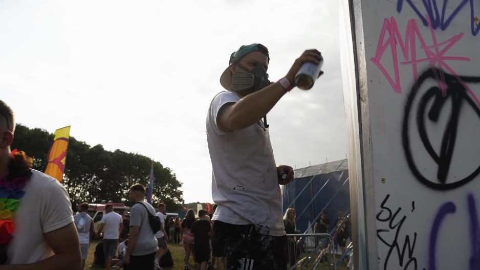 Artist wearing mask while spray painting wall at festival ClipStock