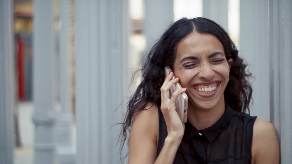 Young Hispanic Woman Smiling And Laughing While Talking On The Phone In