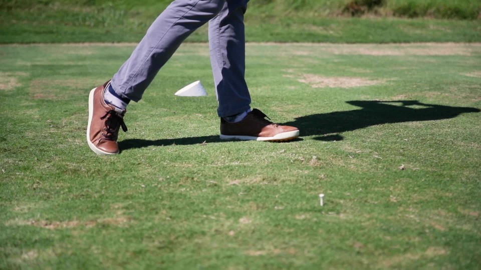 Golfer hitting ball with driver and tee ripped out of the ground below