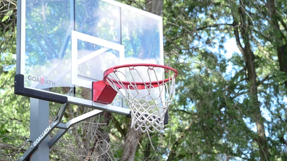 Man missing shot at basketball hoop in parking lot - slow motion