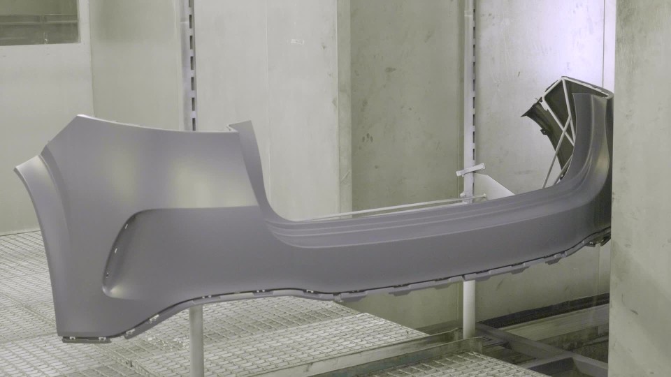 Factory employee assembling front piece of car bumper in production