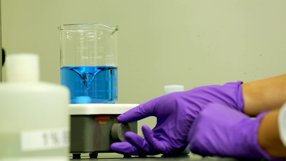 lab tech heating up chemical substance in beaker on hot plate ClipStock