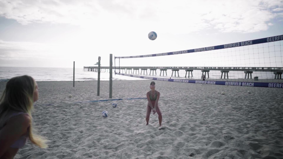 Long shot of girl sending down spike in beach volleyball match slow