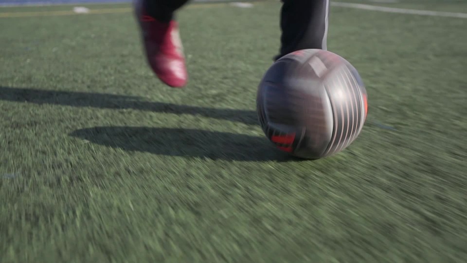 football field with person running by dribbling soccer ball Slow Motion
