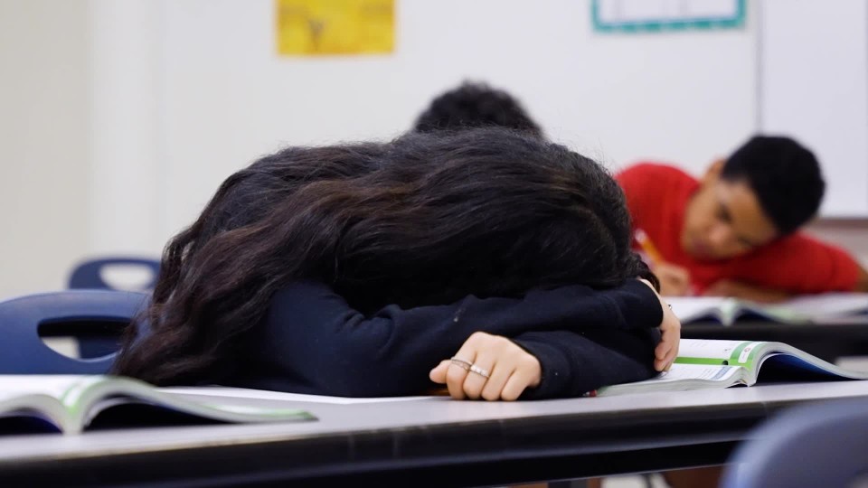 Caring female teacher waking up Asian girl sleeping during class