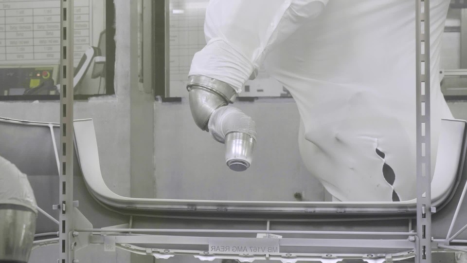 Factory employee assembling front piece of car bumper in production