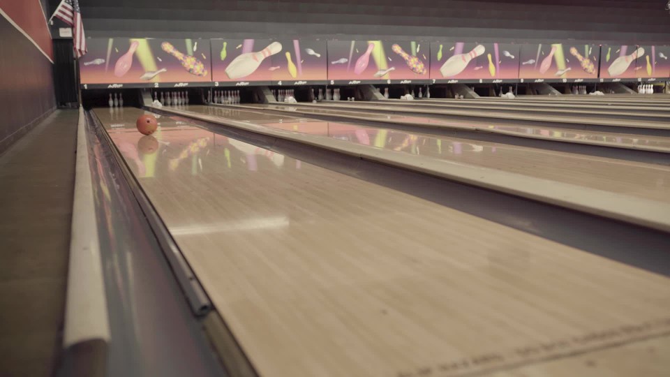 A bowling ball rolling down the lane at a bowling alley in a resort and