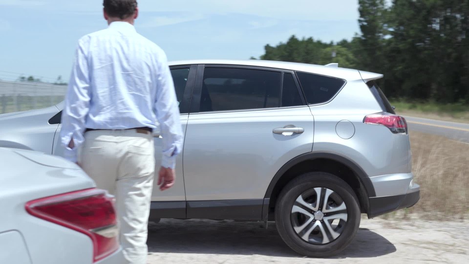 Medium shot of electric car pulling in to spot and man getting out