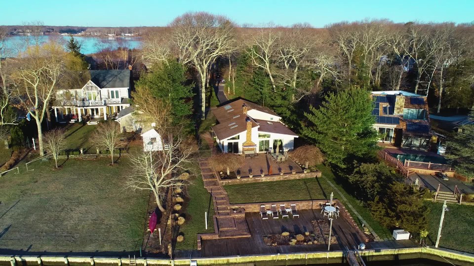 Upper class waterfront home with wooden deck and boat dock in