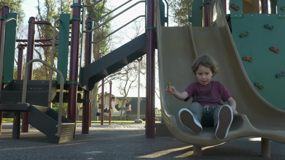 Multiple kids going down slide one by one at playground Slow Motion