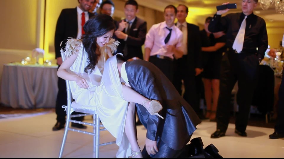 Groom taking off garter belt from bride | ClipStock