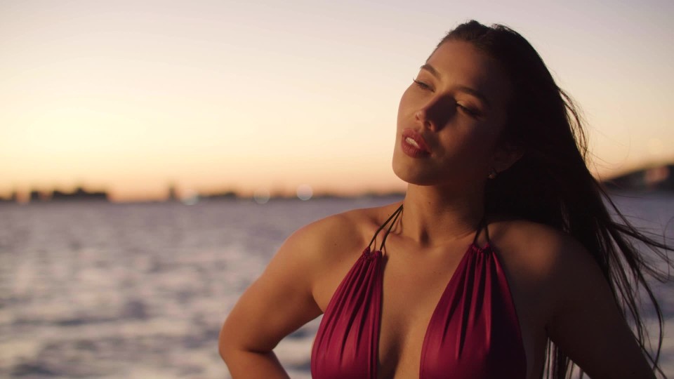 Sexy Latina female in one piece bathing suit posing at the beach during the  evening | ClipStock