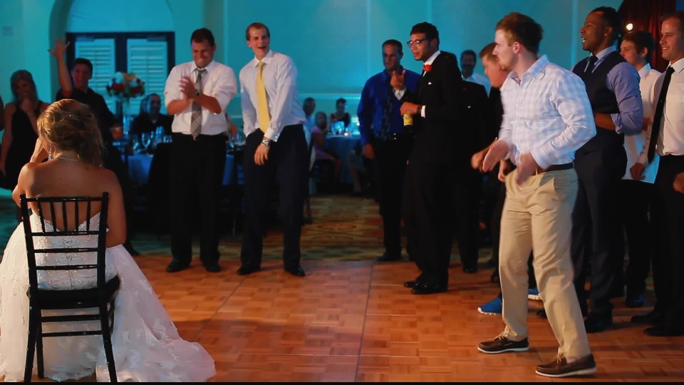 Groom removing bride garter belt with mouth in garter belt toss event |  ClipStock