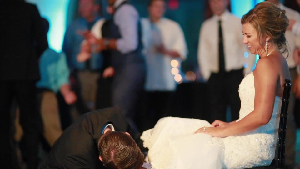 Tight shot left of groom removing garter belt from bride | ClipStock