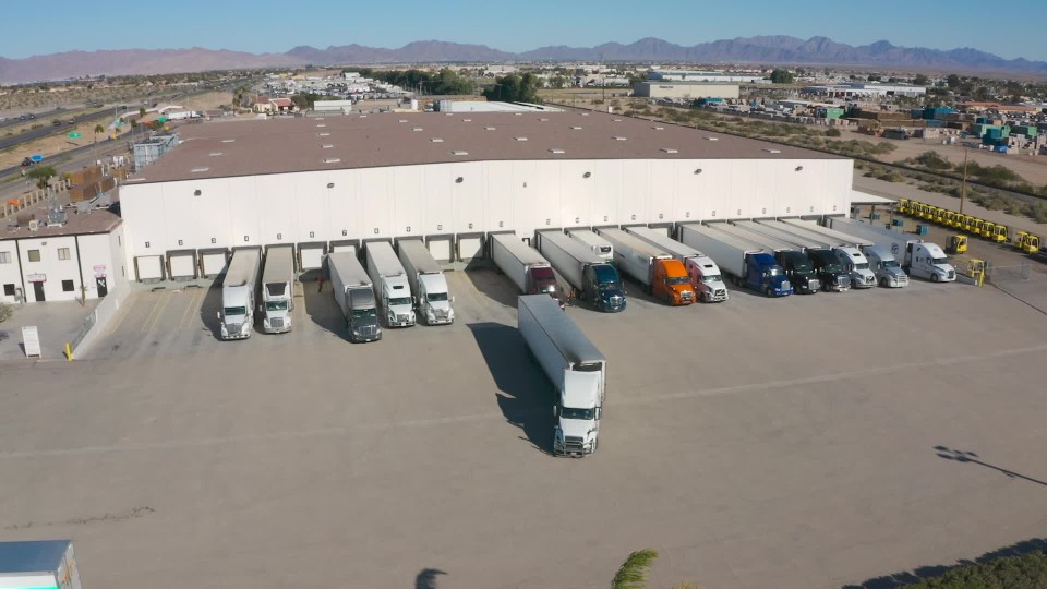 White delivery truck backing up onto loading dock area at compound