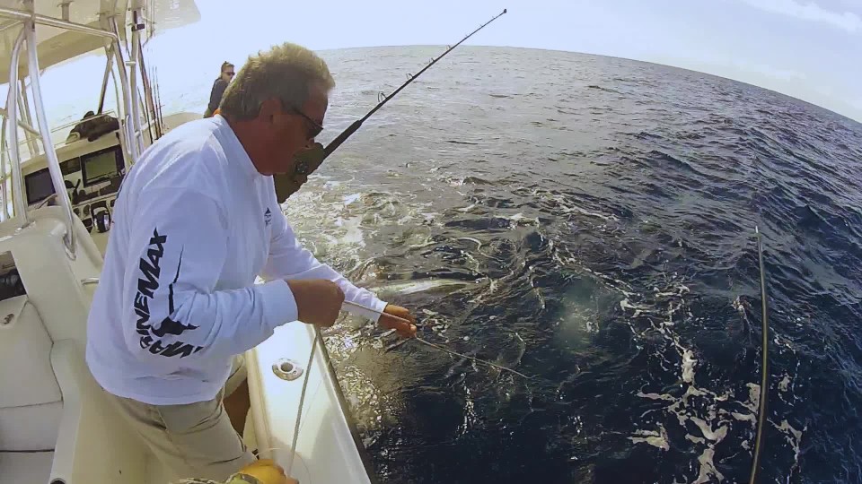 Fishermen catching and gaffing swordfish from center console fishing