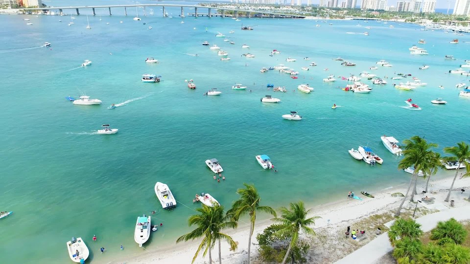 boats anchored and people partying in peanut island ClipStock