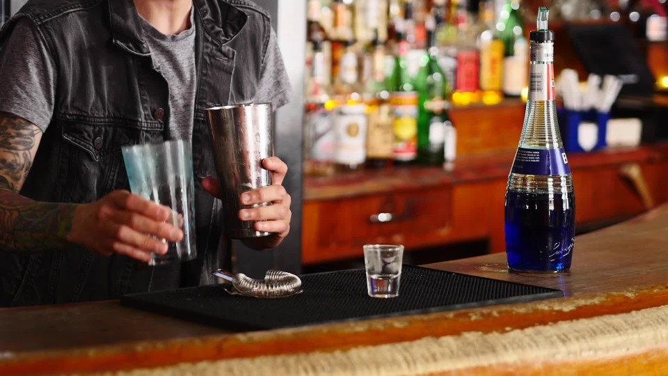 Bartender pouring liquor into a glass on the bar slow motion ClipStock